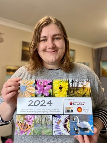 Hannah holding up the 2024 RGF calendar